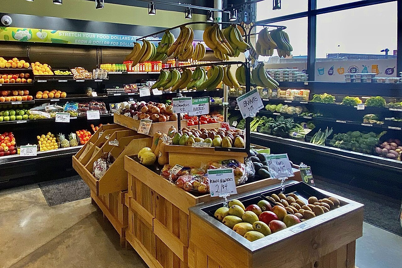Frutas e hortaliças expostas em bancas de um mercado.