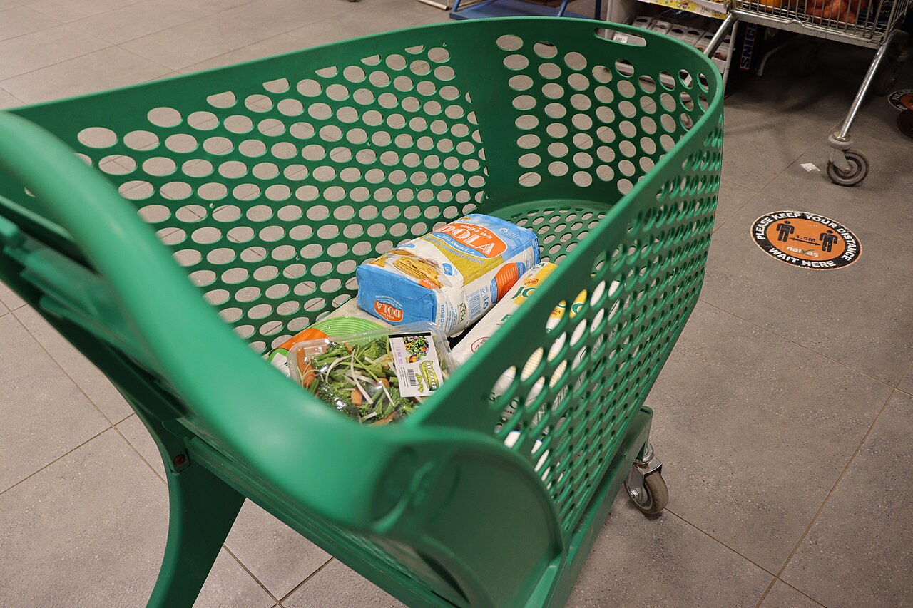 Carrinho de compras com produtos no interior de um supermercado.